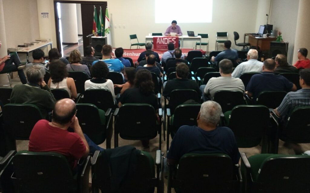 A foto, feita do fundo do auditório, mostra professoras e professores do IFRS de costas, participando da Assembleia de formação do SINDOIF, em dezembro de 2017, no Auditório Rui Cruse, do Campus Porto Alegre do IFRS. O evento contou com a presença de representantes da Regional RS do ANDES-SN e das seções sindicais gaúchas.